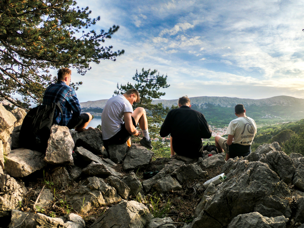 Four Men Seated on Rocks Facing Mountain